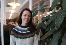 Många unga känner ångest inför vuxenlivet – expert: ”Konstant utsatta för osäkerhet” En bild på Édua Holmström, en kvinna med långt brunt hår och en färgglad tröja. Hon står framför en glasvägg invid en husväxt och ler mot kameran.