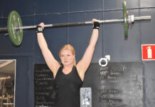 Muskler är inte längre bara för män Kvinna tränar tyngdlyftning med en stång över huvudet