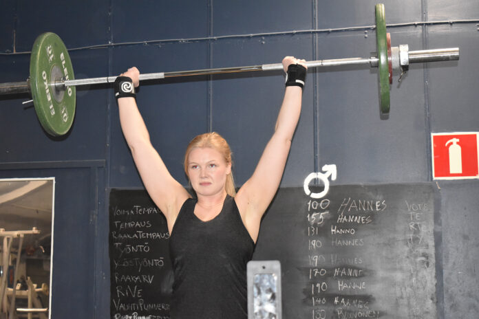 Kvinna tränar tyngdlyftning med en stång över huvudet
