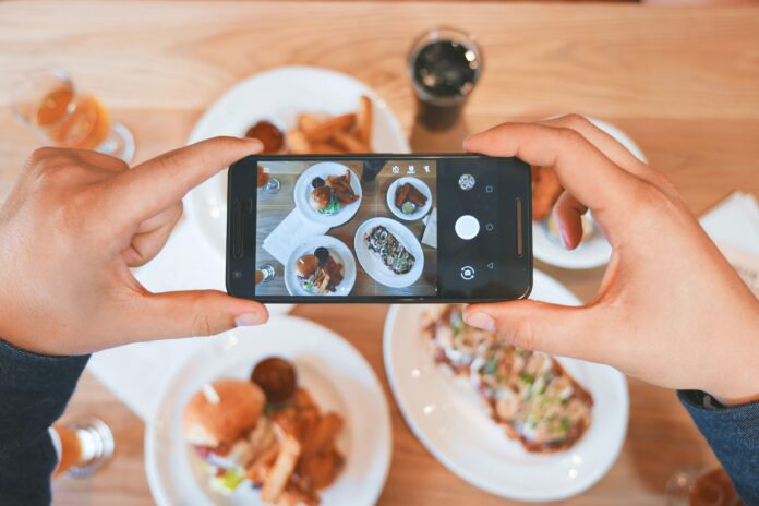 Bild på en smarttelefon som tar en bild av tallrikar med mat.