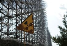 Internationella Minnesdagen för Tjernobylkatastrofen På bilden är en varningssymbol för radioaktivt avfall framför ett högt stängsel. Vädret är soligt.