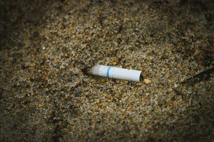 En cigarettfimp på en sandväg.